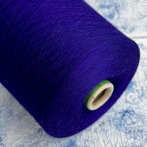 May include: A spool of deep purple yarn with a green and white label.