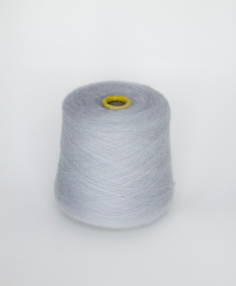 Puede incluir: Una bobina de hilo de color gris claro.