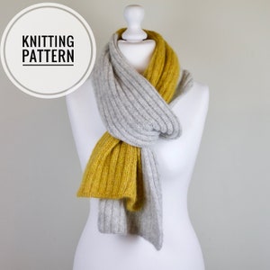 May include: A gray and mustard yellow knitted scarf. The scarf is folded and draped around a white mannequin.