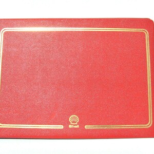 Puede incluir: Álbum de fotos de cuero rojo con borde dorado y logotipo de Shell.
