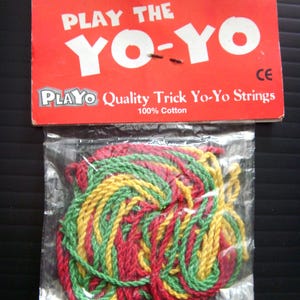 May include: A package of Playo brand yo-yo strings. The strings are red, green, and yellow, and are made of 100% cotton. The packaging is red with white text that reads "PLAY THE YO-YO".