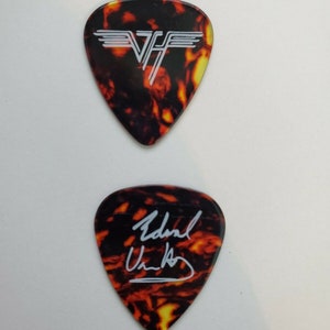 May include: Two guitar picks with a tortoise shell pattern. One pick has the Van Halen logo in white. The other pick has the signature "Eddie Van Halen" in white.