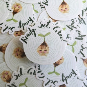 May include: A set of round stickers with a green sprout and a smiling face. The stickers have the text "Ready, Set, Grow!" in green and white lettering.