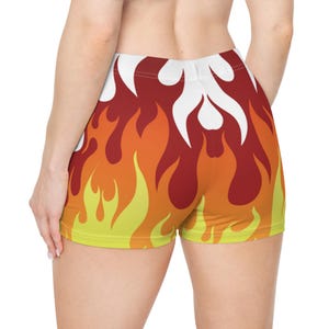 May include: A pair of shorts with a vibrant flame design. The shorts feature a pattern of red, orange, and yellow flames against a white background. The shorts are made of a stretchy material.