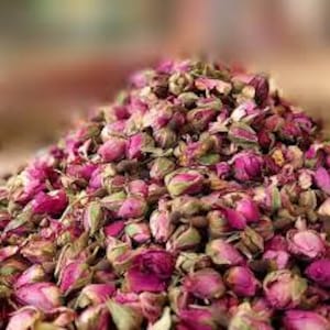 Könnte beinhalten: Nahaufnahme eines Haufens getrockneter Rosenknospen. Die Knospen sind rosa und grün, einige zeigen geöffnete Blütenblätter. Der Hintergrund ist unscharf.