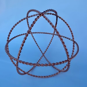 May include: A copper wire sculpture in the shape of a sphere. The wire is twisted and forms a geometric pattern.