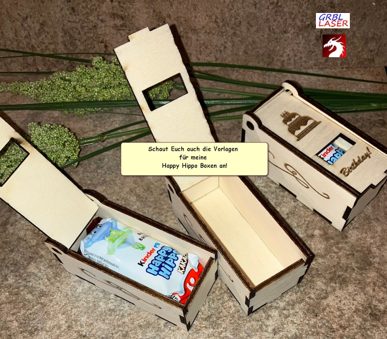 K&ouml;nnte beinhalten: Zwei Holzkisten mit ge&ouml;ffneten Deckeln, die eine Schokoladentafel im Inneren zeigen. Die Kisten sind mit einem Kuchen und den Worten "Happy Hippo Boxen" und "Birthday!" verziert. Die Kisten sind aus hellem Holz und haben eine nat&uuml;rliche Oberfl&auml;che.