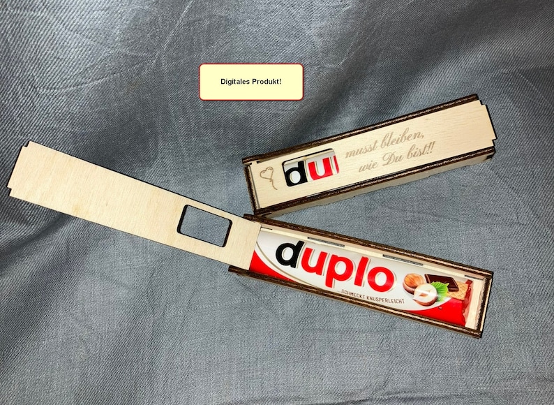 K&ouml;nnte beinhalten: Eine Holzkiste mit einem Schiebedeckel, die f&uuml;r eine Schokoladentafel gedacht ist. Die Kiste ist mit dem Text "du" und "musst bleiben, wie Du bist!!!" graviert. Die Kiste ist ge&ouml;ffnet und eine Schokoladentafel ist im Inneren sichtbar.