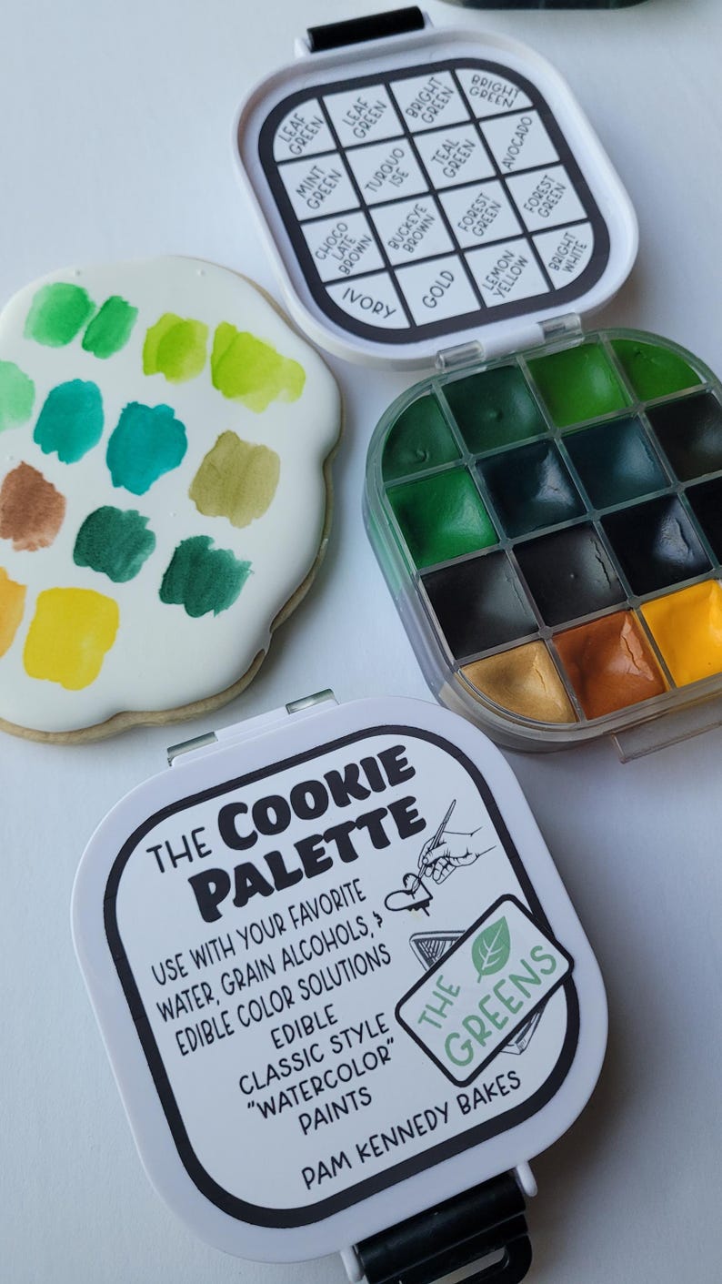 May include: A cookie palette with green watercolor paints and a variety of colors. The palette includes a cookie with green paint swatches, a container of green paints, and a container with color names like "Leaf Green" and "Mint Green".