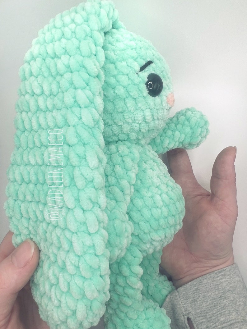 May include: A crocheted plush toy bunny in a light green color. The bunny has large floppy ears and a sweet expression.