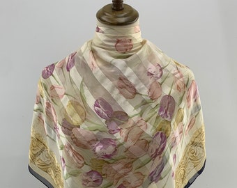 May include: A white silk scarf with a floral print of pink and purple tulips. The scarf has a yellow and gold border with a repeating pattern and the text "Pierre Balmain" in the bottom right corner.