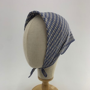 May include: A blue and white checkered bandana with a white border, displayed on a wooden mannequin head.
