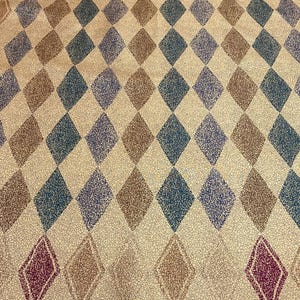 May include: A fabric textile featuring a repeating diamond pattern in shades of dark green, brown, and maroon on a tan background with a fine crackle texture. The top and bottom borders are blue with a repeating graphic of elephants.