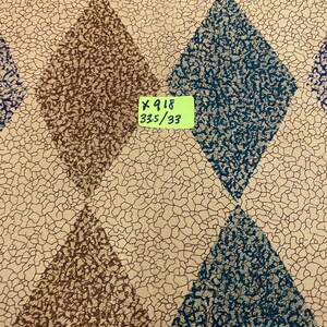 May include: Fabric featuring a repeating diamond pattern in alternating brown and teal textured prints against a cream background with a fine black crackle design. A small yellow label is attached with the text X 918 33.5/33 printed in black.