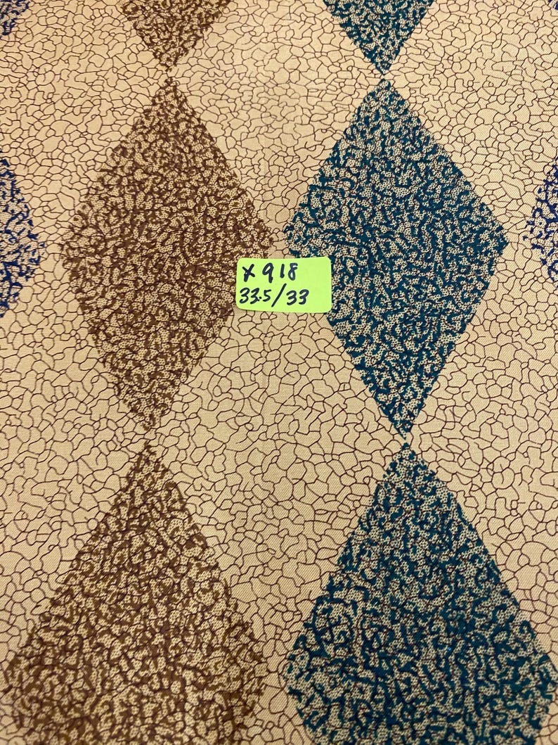 May include: Fabric featuring a repeating diamond pattern in alternating brown and teal textured prints against a cream background with a fine black crackle design. A small yellow label is attached with the text X 918 33.5/33 printed in black.