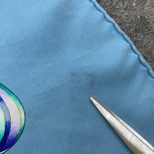 May include: A light blue silk scarf with a colourful abstract design. The scarf has a small stain on the fabric.