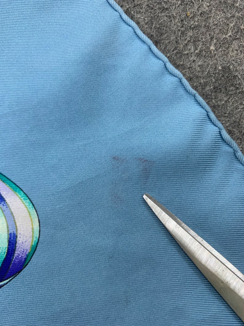 May include: A light blue silk scarf with a colourful abstract design. The scarf has a small stain on the fabric.