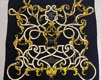 May include: Black silk scarf with a gold and white ornate design. The scarf features intricate patterns, including equestrian-themed elements and text that reads "Hermès Paris". The scarf is square in shape.