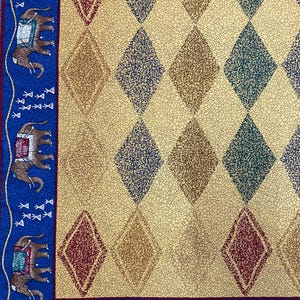 May include: A fabric textile featuring a cream-colored background with a repeating diamond pattern in shades of red, blue, and green. A blue border runs along the edge, decorated with a repeating motif of brown elephants and small white symbols.