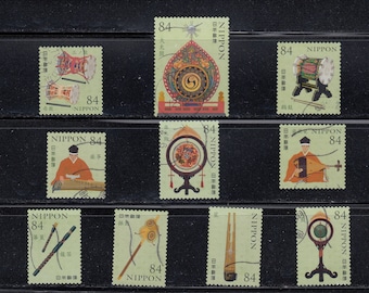 May include: A collection of nine Japanese postage stamps, each featuring a different traditional musical instrument or musician. The stamps are green with the number 84 and the word "NIPPON" printed on them.