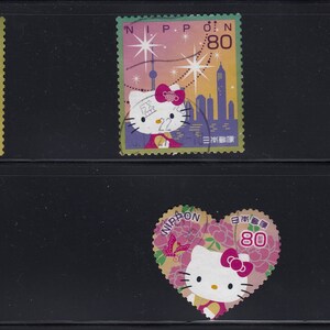 May include: A collection of five Japanese postage stamps featuring Hello Kitty. The stamps showcase various designs, including iconic landmarks and floral motifs. Each stamp has a value of 80, with the word "NIPPON" printed on them.