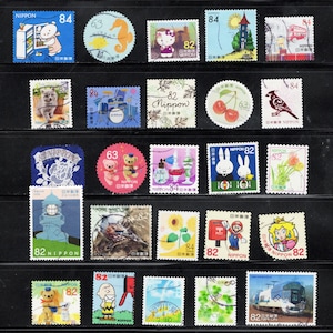Puede incluir: Una colecci&oacute;n de varios sellos postales japoneses dispuestos en filas sobre una hoja de presentaci&oacute;n negra. Los sellos presentan diversas ilustraciones que incluyen animales, personajes de dibujos animados, paisajes, flores, comida y transporte, con valores como 63, 82 y 84.