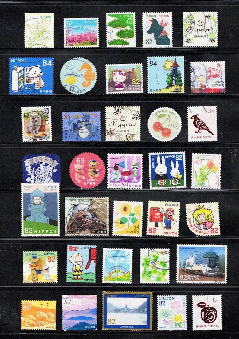 Puede incluir: Una colecci&oacute;n de varios sellos postales japoneses dispuestos en filas sobre una hoja de presentaci&oacute;n negra. Los sellos presentan diversas ilustraciones que incluyen animales, personajes de dibujos animados, paisajes, flores, comida y transporte, con valores como 63, 82 y 84.