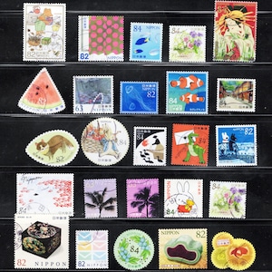 Puede incluir: Una colecci&oacute;n de veinticuatro sellos postales japoneses dispuestos en cinco filas. Los sellos presentan diversas ilustraciones que incluyen animales, flores, comida, paisajes y motivos culturales, con valores de 62, 63, 82 y 84.
