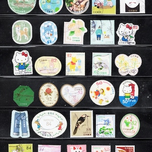 Puede incluir: Una colecci&oacute;n de veinticinco sellos postales japoneses dispuestos en cinco filas. Los sellos presentan diversas ilustraciones que incluyen peces, personajes de dibujos animados como Hello Kitty y Winnie the Pooh, flores, aves y motivos japoneses tradicionales con varios valores nominales.