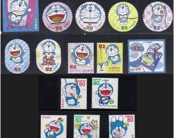 Puede incluir: Colección de coloridos sellos postales japoneses con el personaje de dibujos animados Doraemon. Los sellos muestran a Doraemon en varias poses, con los números 80 y 82 en un lugar destacado. También se ve la palabra "NIPPON".