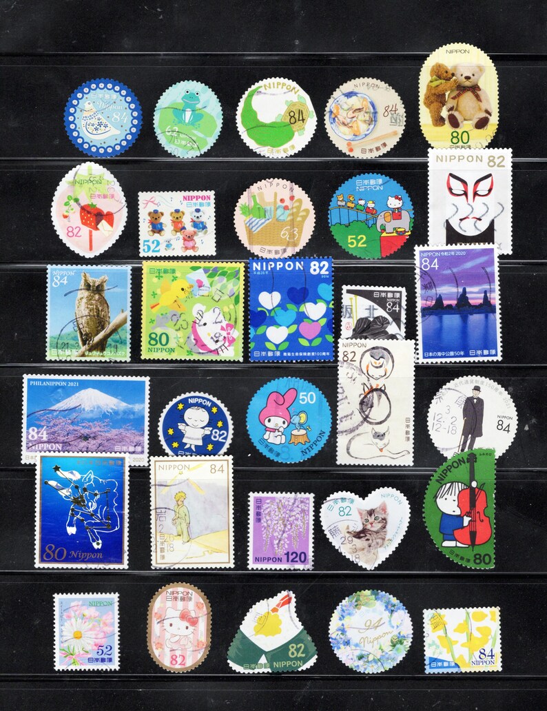 Puede incluir: Una colecci&oacute;n de diversos sellos postales japoneses con ilustraciones variadas que incluyen animales, flores, paisajes y personajes. Los sellos var&iacute;an en forma, incluyendo dise&ntilde;os circulares, rectangulares y en forma de coraz&oacute;n, con denominaciones de 50, 52, 63, 80, 82, 84 y 120.