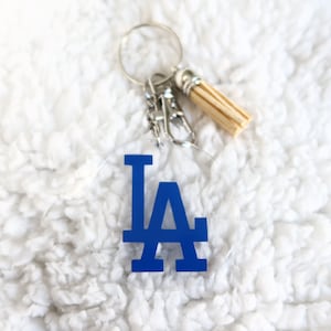 May include: A blue LA keychain with a silver key ring and a wooden tassel.