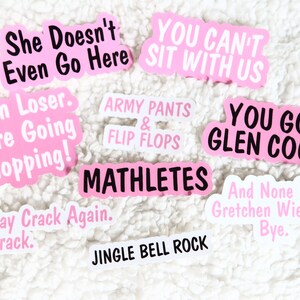 Op de afbeelding: Een verzameling roze en witte stickers met verschillende zinnen, waaronder "She Doesn't Even Go Here", "Get In Loser. We're Going Shopping!" en "You Go Glen Coco".