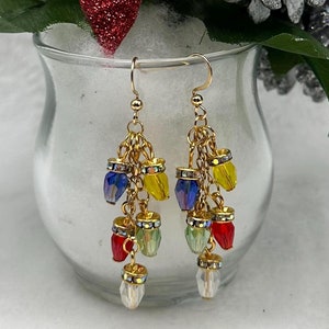 May include: Gold dangle earrings with multi-colored crystal beads. The earrings feature a cascading design with red, yellow, green, and blue beads.