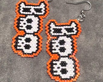 Pendientes colgantes “Boo” de Halloween con cuentas de semillas Miyuki Delica en naranja, negro y blanco, acabados con alambre de acero inoxidable en tono plateado.