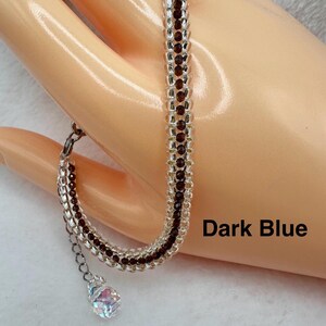 May include: A dark blue and clear beaded bracelet with a crystal charm. The bracelet is made with small seed beads and has a delicate, elegant look.