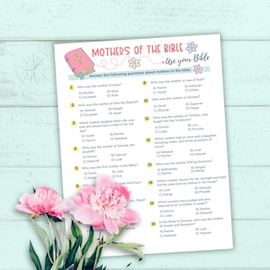 May include: A printed sheet with the title "Mothers of the Bible" and questions about mothers in the Bible. The sheet is decorated with floral graphics and a pink book illustration. Pink flowers are in the foreground.