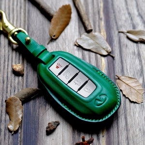 May include: Green leather key fob with a silver key chain and four buttons. The buttons have symbols for heated seats, unlock, lock, and boot release.