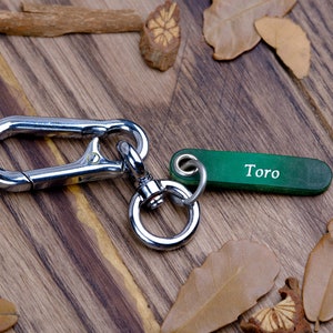 May include: A silver key chain with a large carabiner clip and a green tag that says "Toro".