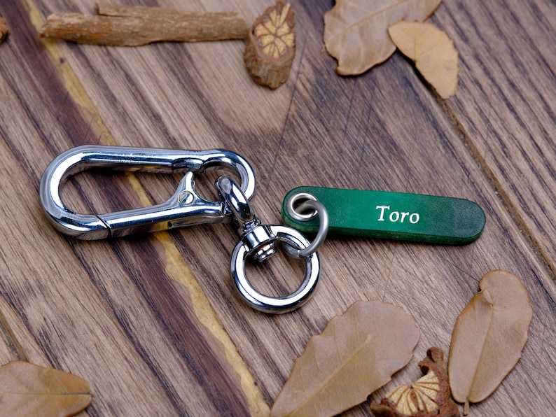 May include: A silver key chain with a large carabiner clip and a green tag that says "Toro".