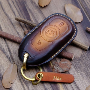 May include: A brown leather key fob with a gold metal key ring and a personalized leather tag that says "Max".