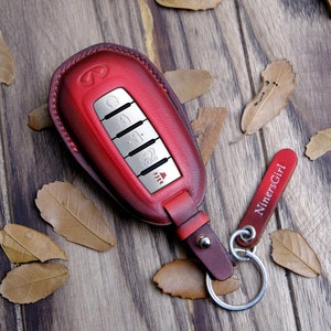 May include: Red leather key fob with a silver key chain and a silver key with multiple buttons. The key fob has the word "NinersGirl" on it.
