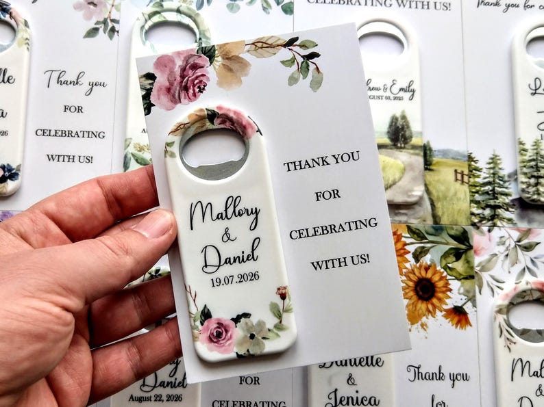 K&ouml;nnte beinhalten: Wei&szlig;er Flaschen&ouml;ffner mit floralen Akzenten und den Namen "Mallory & Daniel" sowie dem Datum "19.07.2026". Eine Karte lautet: "Danke, dass Sie mit uns feiern!" Ideal f&uuml;r Hochzeiten oder Partys.