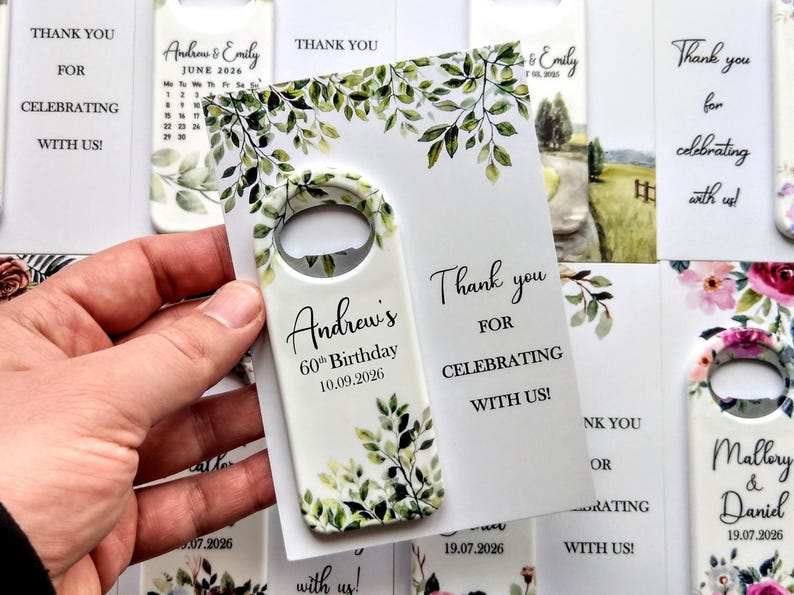 May include: A white bottle opener with a floral design and the text "Andrew's 60th Birthday 10.09.2026". The opener is held next to a card that says "Thank you for celebrating with us!"
