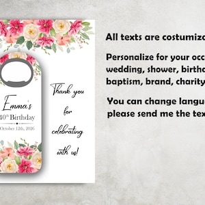 May include: A white door hanger with a bottle opener cutout, decorated with pink and cream floral arrangements. The text reads "Emma's 40th Birthday October 12th, 2026" and "Thank you for celebrating with us!" Additional text states all texts are customizable.