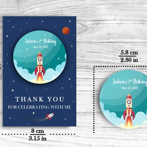 May include: A blue and teal thank you card with a rocket ship and stars. The card reads "Jackson's 2nd Birthday" and "Thank you for celebrating with me". The card measures 4.7 inches by 3.15 inches.