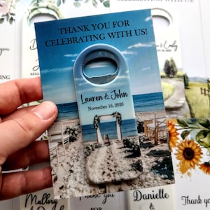 K&ouml;nnte beinhalten: Ein Flaschen&ouml;ffner mit Strandhintergrund, mit dem Text "Thank you for celebrating with us!" und den Namen "Lauren & John" mit dem Datum "November 16, 2026". Weitere Karten mit Blumen- und Landschaftsmotiven sind sichtbar.