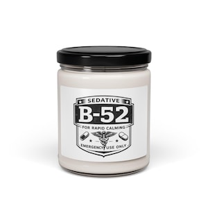May include: A white jar with a black lid featuring a label with the text "SEDATIVE B-52 FOR RAPID CALMING EMERGENCY USE ONLY". The label includes a shield design with a caduceus symbol and pill illustrations.