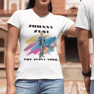 Może przedstawiać: Dwie osoby w białych koszulkach z napisem "Johnny Zest" i rozkładem trasy koncertowej nadrukowanym na plecach. Rozkład trasy koncertowej zawiera daty i lokalizacje koncertów.