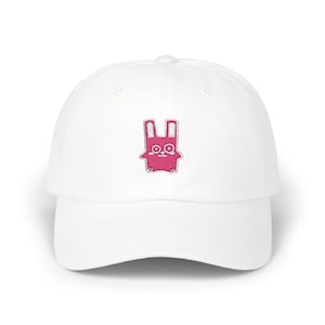 Può includere: Cappellino da baseball bianco con un design di coniglio rosa ricamato.